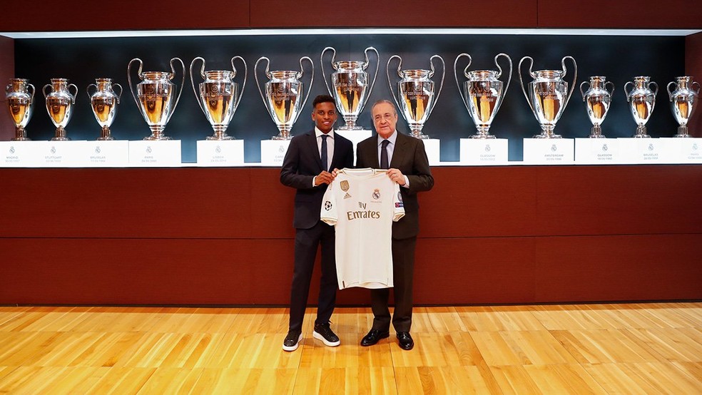 Rodrygo e Florentino Pérez mostram camisa do Real Madrid diante das 13 taças da Liga dos Campeões conquistadas pelo clube — Foto: Reprodução de Twitter