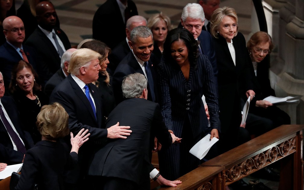 O ex-presidente dos EUA George W. Bush se curva por cima de Donald e Melania Trump para cumprimentar a ex-primeira dama Michelle Obama, durante o funeral de George W.H. Bush, na Catedral Nacional de Washington, na quarta-feira (5) — Foto: Reuters/Kevin Lamarque