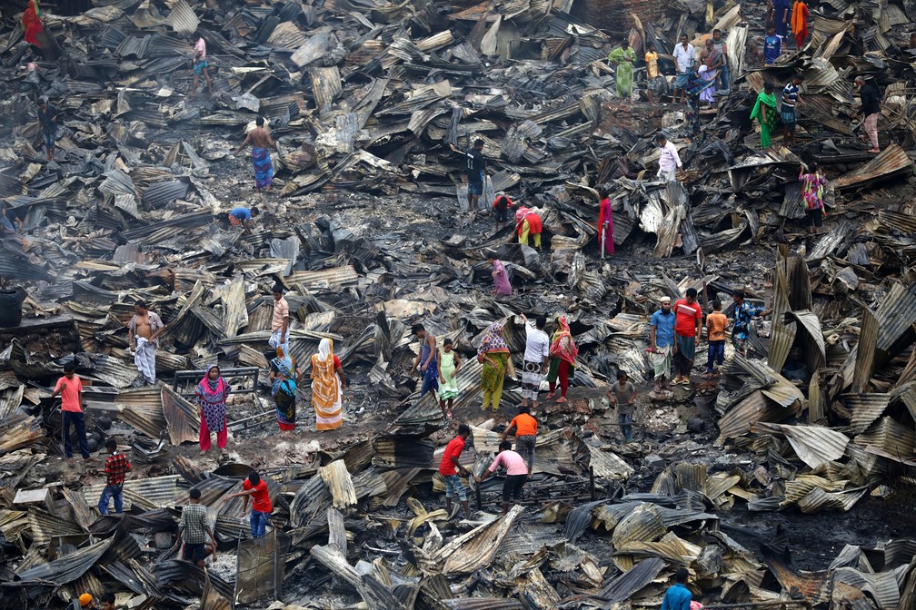 Pessoas procuram pertences em escombros de casas atingidas por incêndio neste sábado (17), em Bangladesh — Foto: Mohammad Ponir Hossain/Reuters