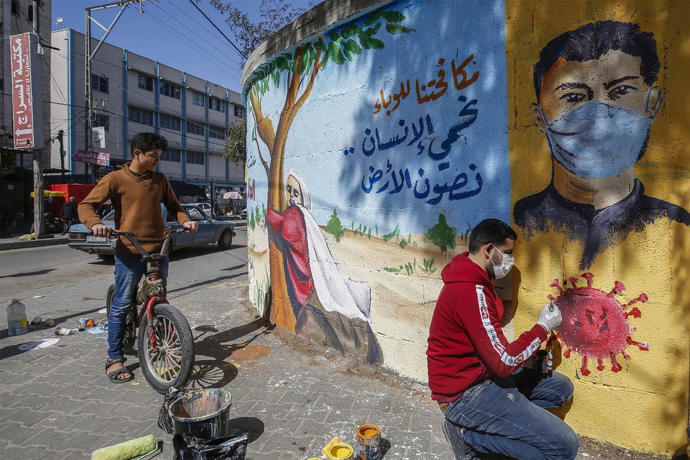 29 de março - Artista palestino finaliza um mural com a frase: 'Combatendo a epidemia, nós protegemos o ser humano e preservamos a Terra', em Rafah, no sul da Faixa de Gaza — Foto: Mohammed Abed/AFP
