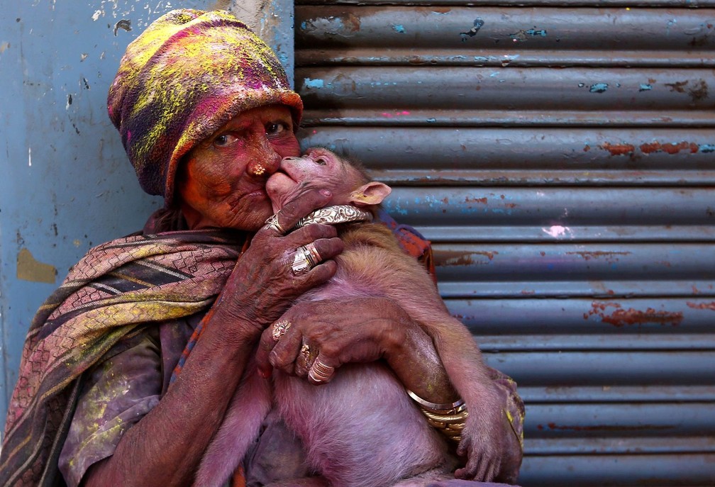 3 de marÃ§o â Mulher posa com seu macaco de estimaÃ§Ã£o, ambos cobertos de pÃ³ colorido do festival hindu Holi em Chennai, na Ãndia. No chamado 'festival das cores', participantes fazem guerra de tinta e pÃ³ colorido celebrando o tempo quente, a colheita e a vitÃ³ria sobre o mal â Foto: P. Ravimukar/Reuters