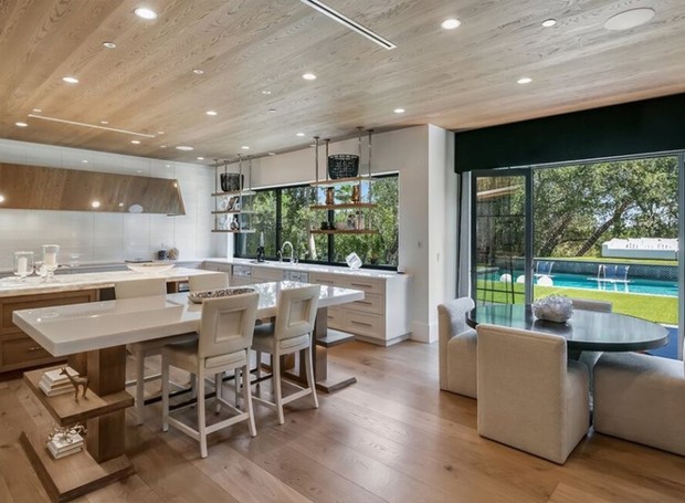 COZINHA | A cozinha se integra com a sala de família (lado oposto) e tem toda marcenaria pautada em tons claros, incluindo no teto (Foto: Reprodução / Realtor)