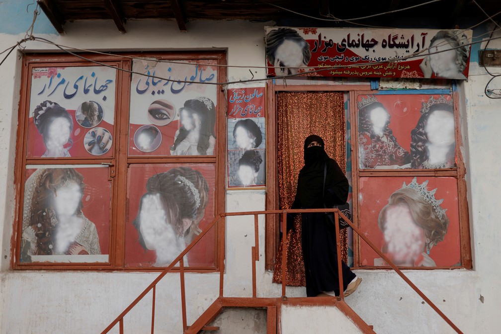 6 de outubro - Uma mulher vestindo um nicabe entra em um salão de beleza onde os anúncios contendo mulheres foram desfigurados por um lojista em Cabul, no Afeganistão   — Foto: Jorge Silva/Reuters