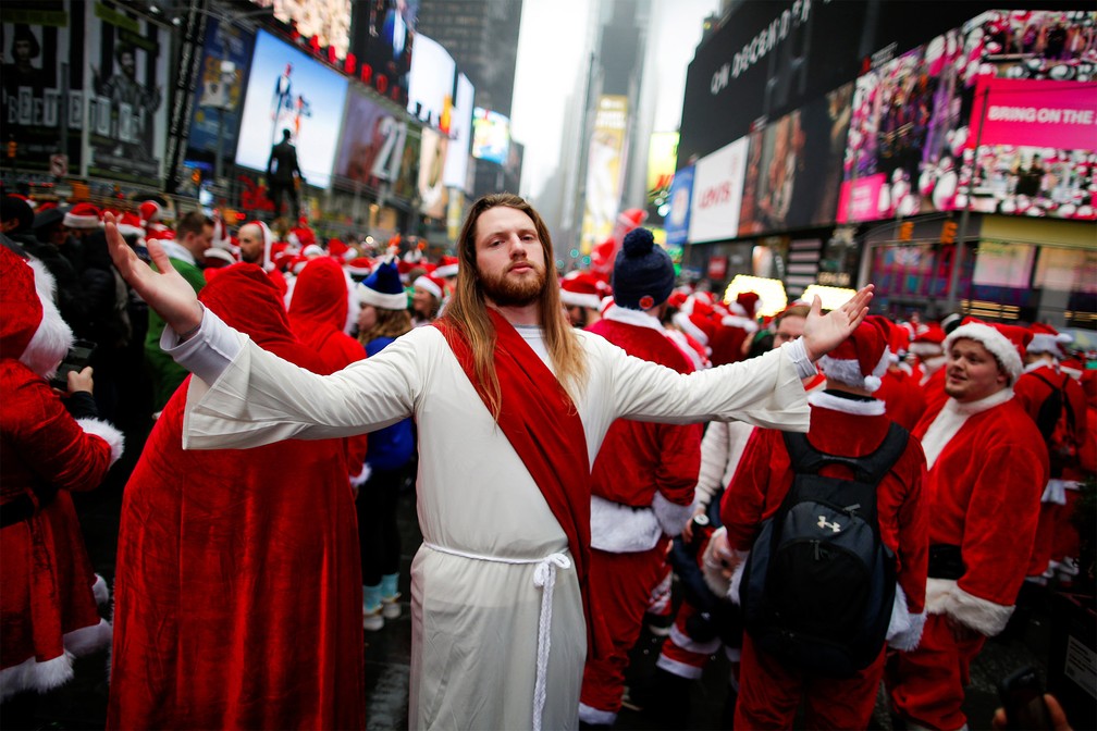 Entre diversos papais noéis, um homem fantasiado de Jesus Cristo faz pose na Times Square, em Nova York, durante evento apelidado de SantaCon, no sábado (14) — Foto: Eduardo Muñoz/Reuters