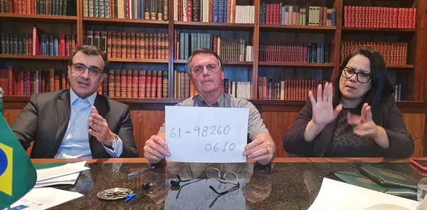 Ao lado do ministro Carlos França durante transmissão ao vivo por redes sociais, Bolsonaro exibe número de telefone para atendimento a brasileiros que estejam na Ucrânia   — Foto: Reprodução / YouTube