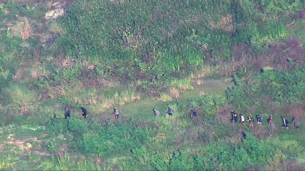 Homens cruzam área de mata densa na Cidade de Deus — Foto: Reprodução/TV Globo