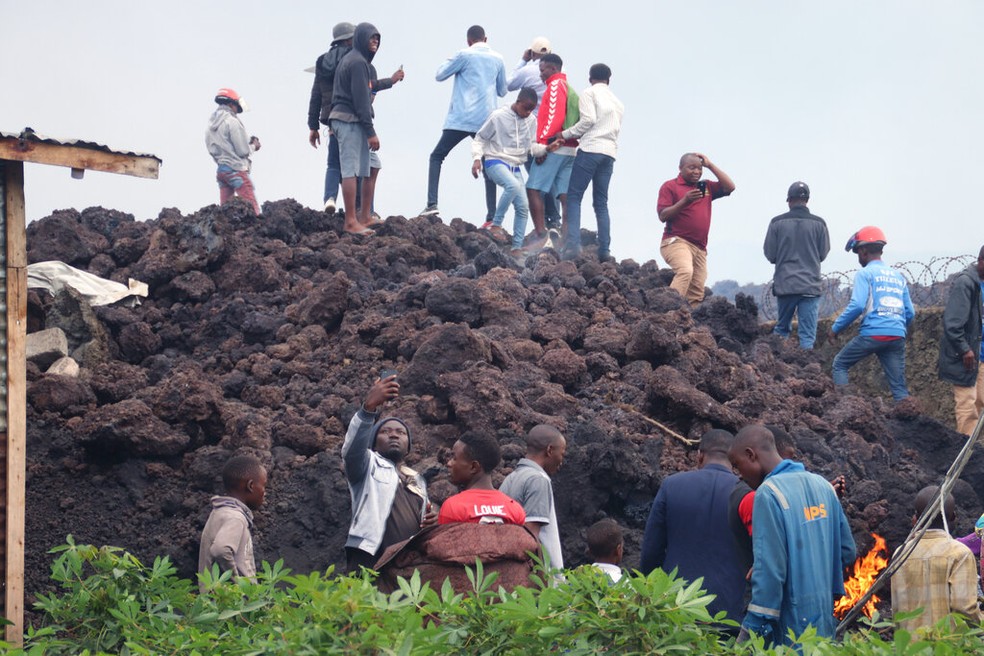 Moradores da região de Goma, na República Democrática do Congo, sobem no domingo (23) em morro de magma frio despejado pela erupção do vulcão Nyiragongo — Foto: Justin Kabumba/AP