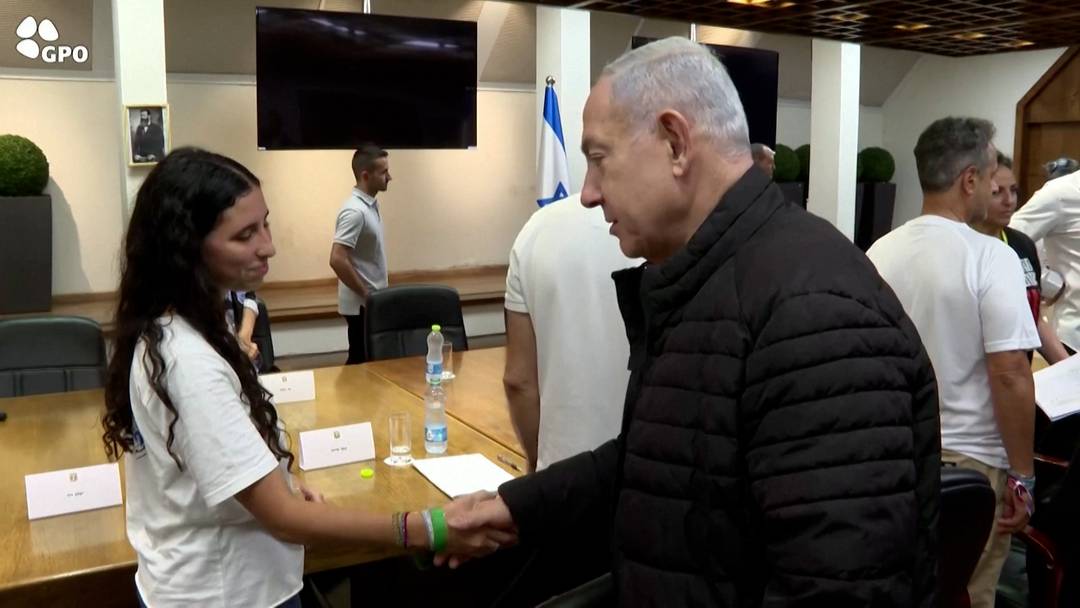 Netanyahu ( esq) aperta mo de mulher que  familiar de um dos refns em Gaza, neste sbado (28)