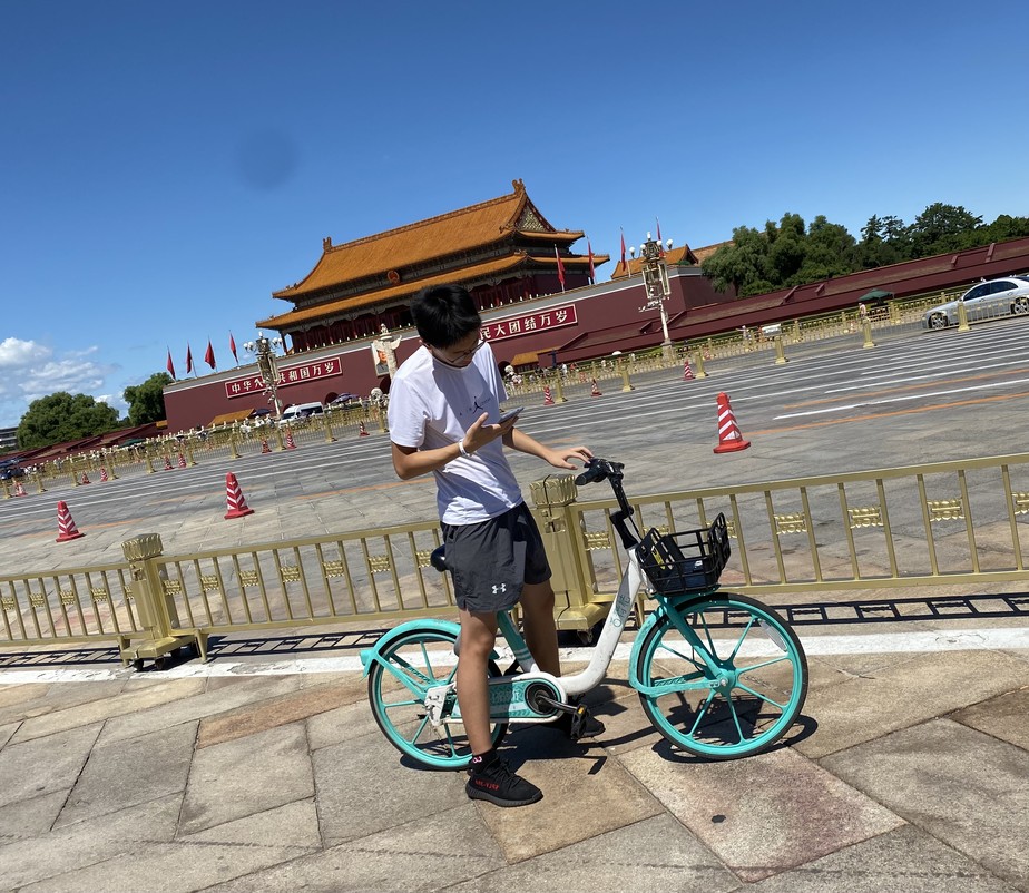 Ciclista consulta celular diante da Cidade Proibida, em Pequim