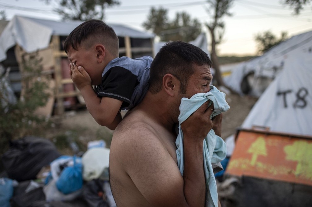 Pai e filho choram após incêndio em campo de migrantes na ilha de Lesbos, na Grécia, neste domingo (29) — Foto: Angelos Tzortzinis/AFP