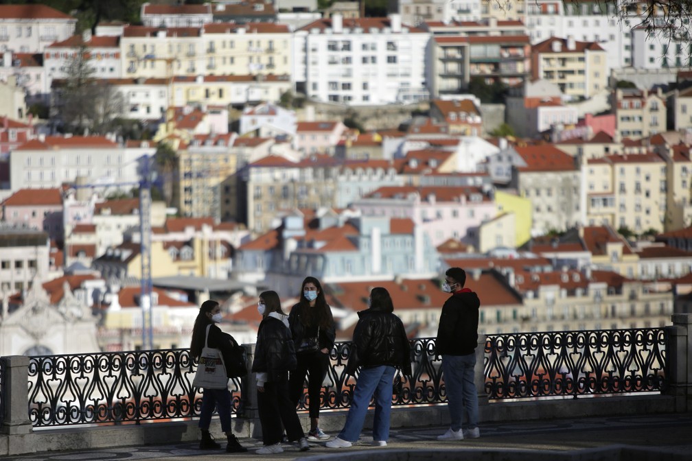 Grupo de jovens com máscaras conversam em mirante com vista para o centro antigo de Lisboa em 11 de março de 2021 — Foto: Armando Franca/AP
