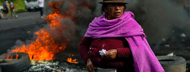 Mulher indígena participa de bloqueio em estrada para protestar contra alta nos combustíveis, no sul de Quito, Equador — Foto: VERONICA LOMBEIDA / AFP