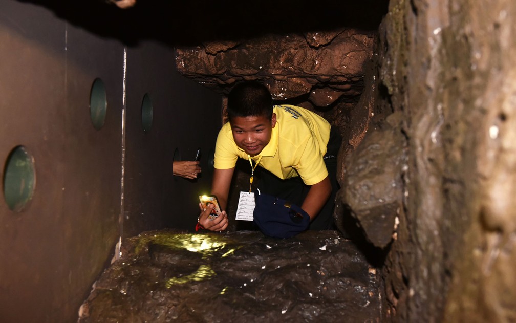 Phanumas Saengdee, um dos integrantes do time ‘Javalis Selvagens’, rasteja por réplica da caverna onde ficou preso em uma exposição interativa montada em Bangcoc, na Indonésia, na quinta-feira (6) (Foto: Panumas Sanguanwong/Thai News Pix/AFP)
