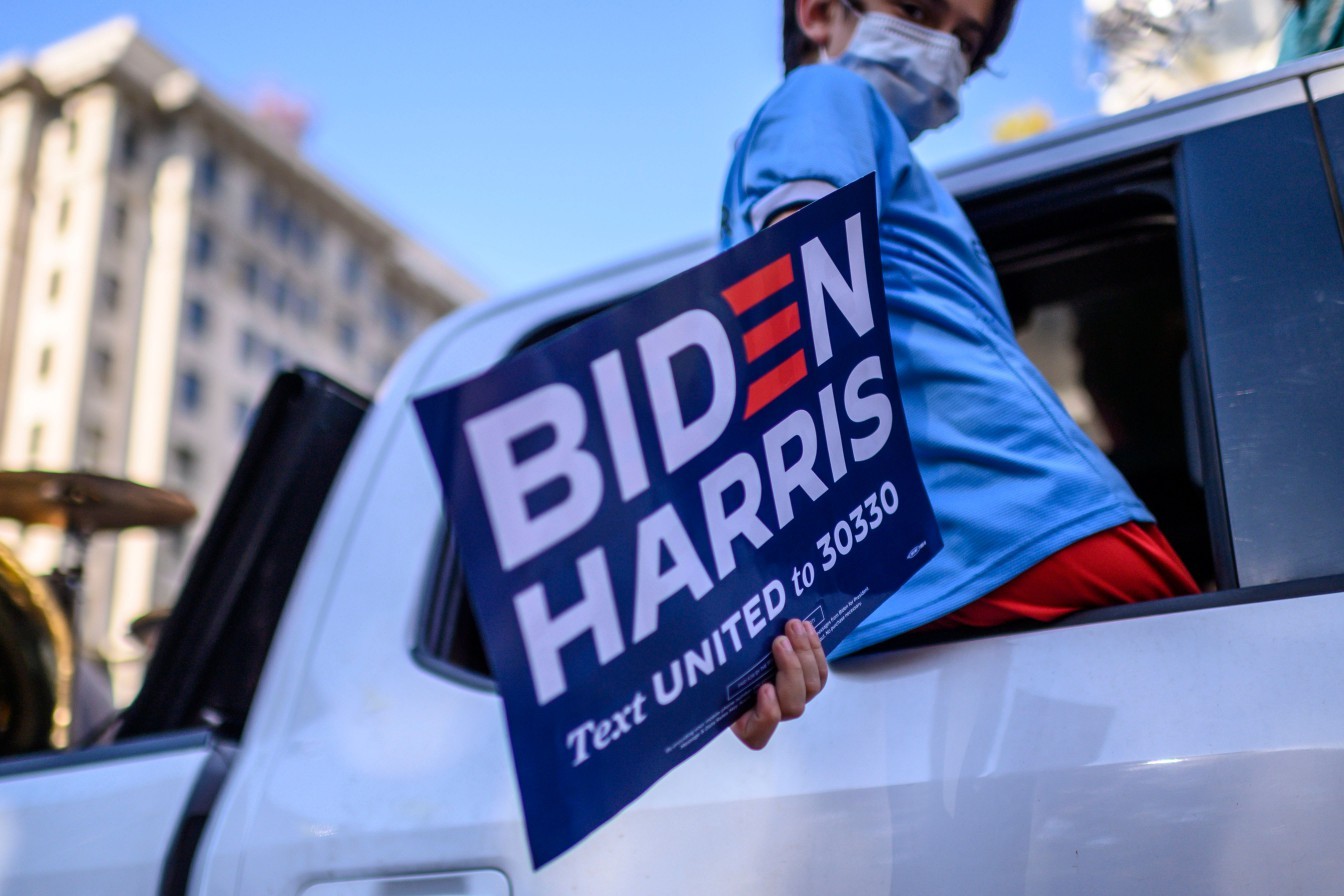 Apoiador de Joe Biden carrega cartaz da campanha democrata durante comemorações em Washington