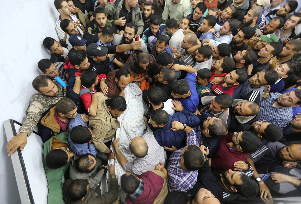 Palestinos carregam corpo de morto em bombardeio contra túnel (Foto: Reuters/Ibraheem Abu Mustafa)