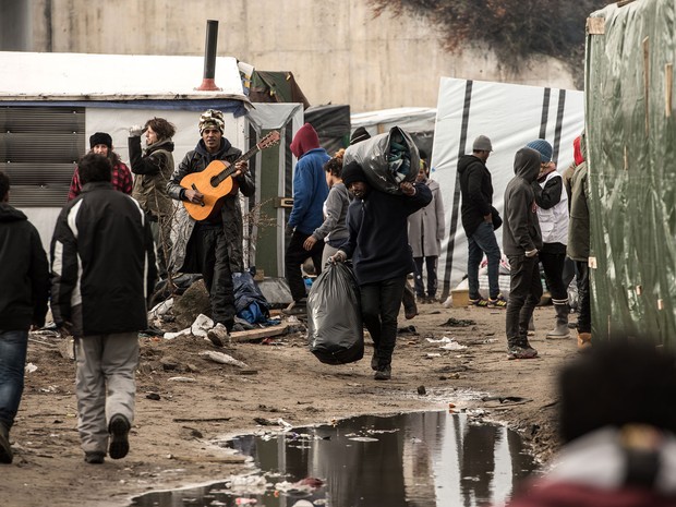 Migrantes carregam pertences no campo de refugiados ‘A selva’, em Calais, na quinta (14), depois que autoridades determinaram evacuação de parte do local (Foto: AFP Photo/Philippe Huguen)