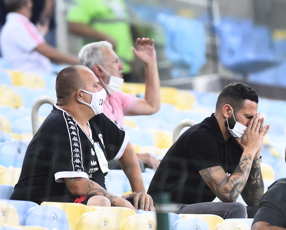 Castan põe as mãos no rosto, enquanto, ao fundo, José Luis Moreira, vice de futebol vascaíno, esbraveja — Foto: André Durão
