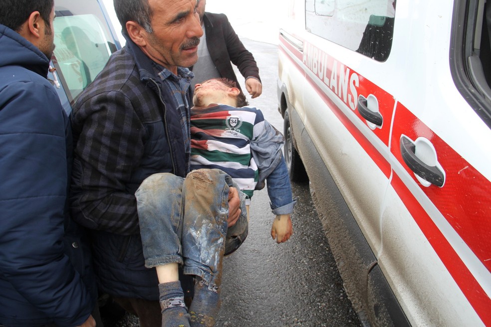 Homem carrega criança feriada após terremoto na Turquia neste domingo (23) — Foto: IHA via AP