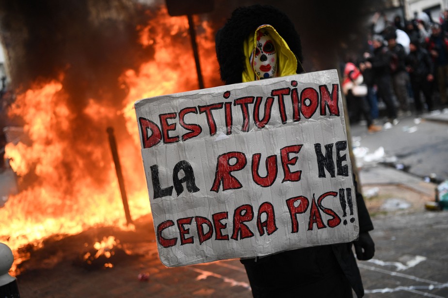 Manifestante segura placa pedindo impeachment do presidente francês Emmanuel Macron e manda recado: 'as ruas não cederão'