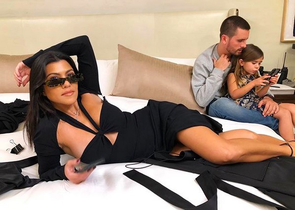 A socialite Koutney Kardashian com o ex-marido brincando ao fundo com um filho (Foto: Instagram)