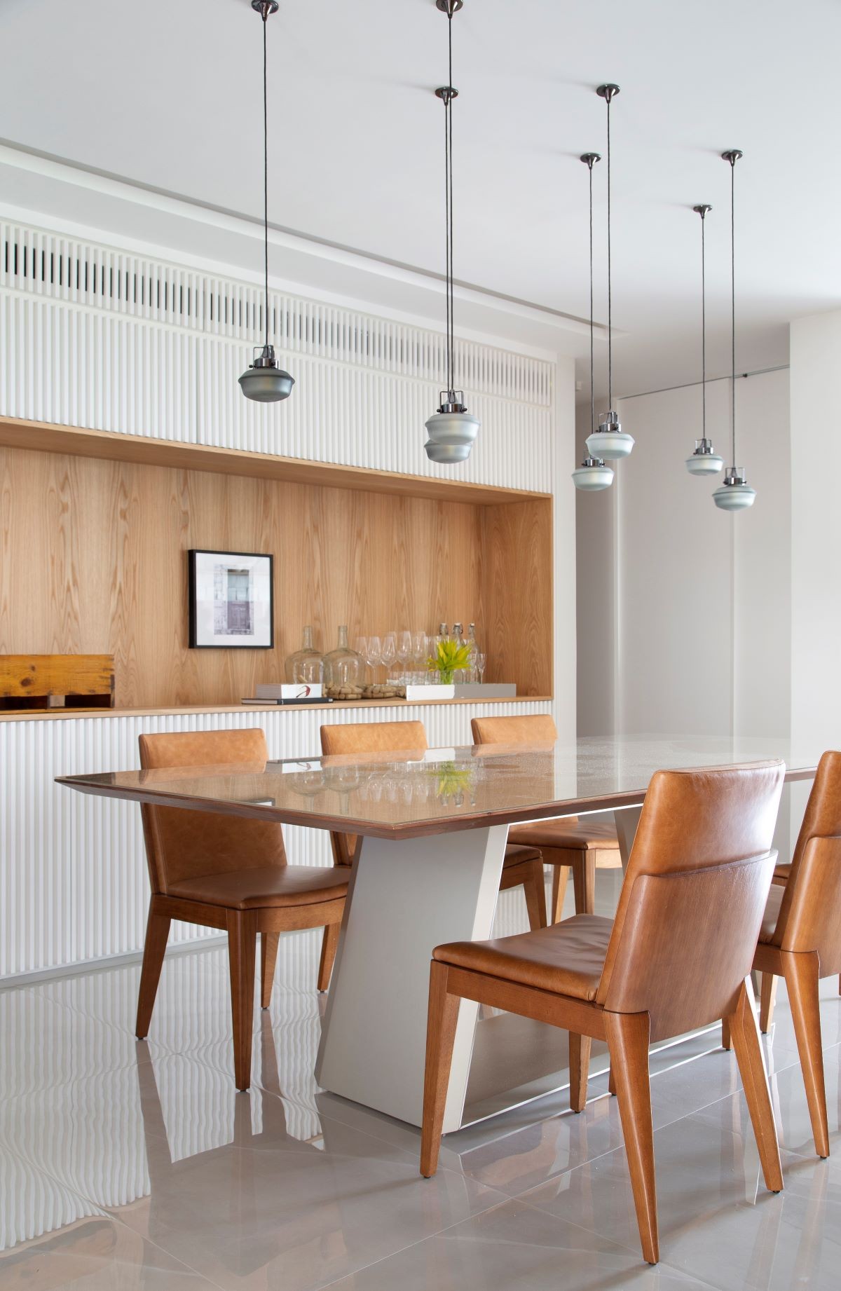 DINING ROOM |  In the dining room, one of the walls has a niche in natural oak, which acts as a sideboard and serves as a support for the table.  The woodwork with slats hides the wardrobe door (Photo: Denilson Machado / MCA Estúdio / Publicity)