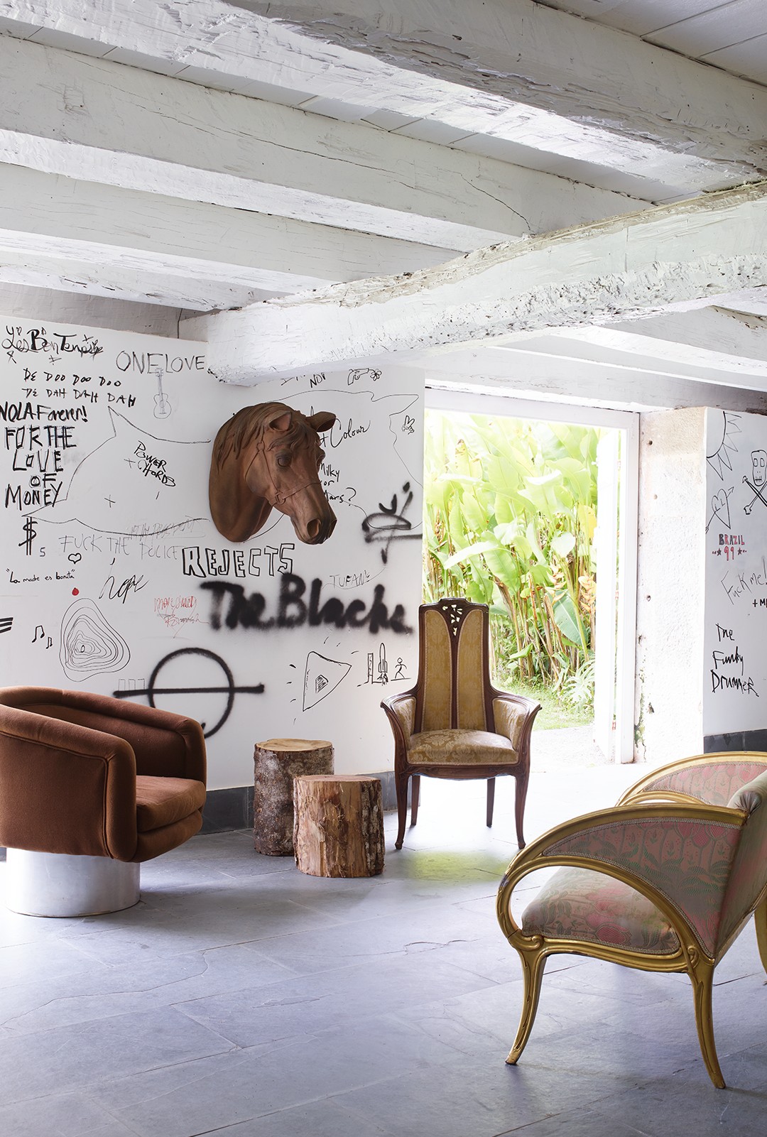 O refúgio brasileiro de Kravitz: Desenhos de Kravitz e amigos nas paredes de uma sala com cadeira giratória dos anos 70 e móveis do início do século 20.  (Foto: Simon Upton)
