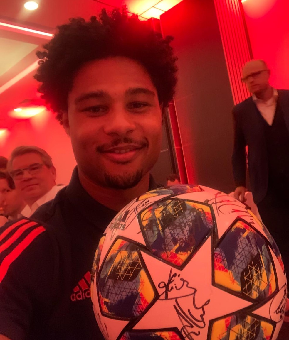 Gnabry com a bola da vitória do Bayern de Munique sobre o Tottenham Hotspur autografada pelos companheiros — Foto: Reprodução de Twitter