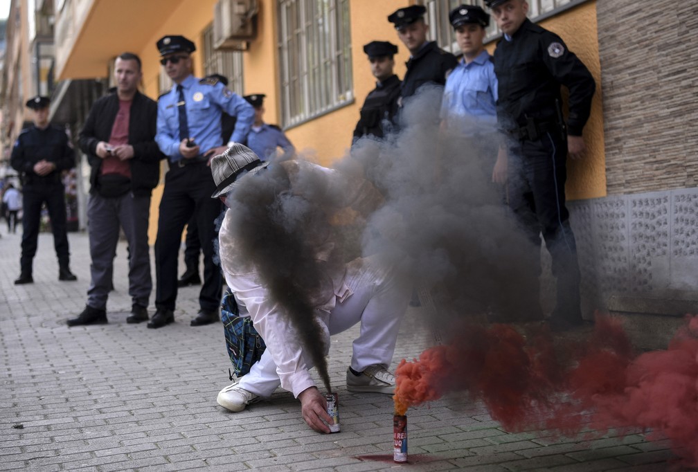 Manifestante coloca sinalizadores em frente ao Ministério do Trabalho e Bem-Estar Social em Pristina, capital do Kosovo, em 1º de maio de 2023 — Foto: Armend Nimani/AFP