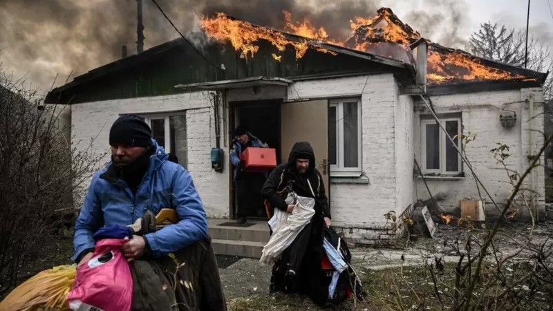 Pessoas abandonam casa em chamas na cidade de Irpin (Foto: Getty Images via BBC)