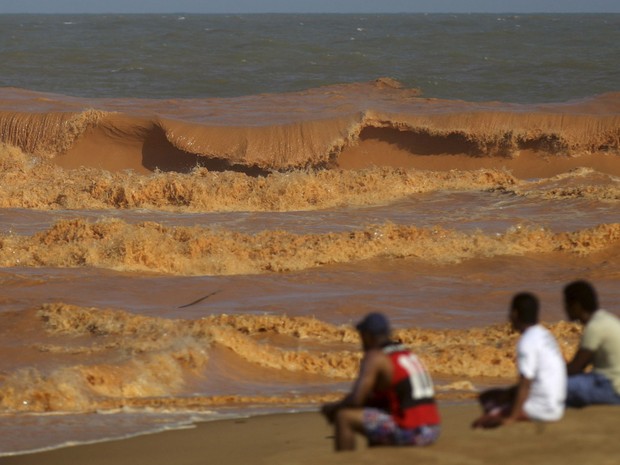 Homens observam uma onda de lama se quebrar na praia em Regência, no Espírito Santo. O local foi atingido pela lama após o rompimento de barragens de rejeitos da mineradora Samarco, cujos donos são a Vale e a australiana BHP, levada pelo Rio Doce  (Foto: Ricardo Moraes/Reuters)