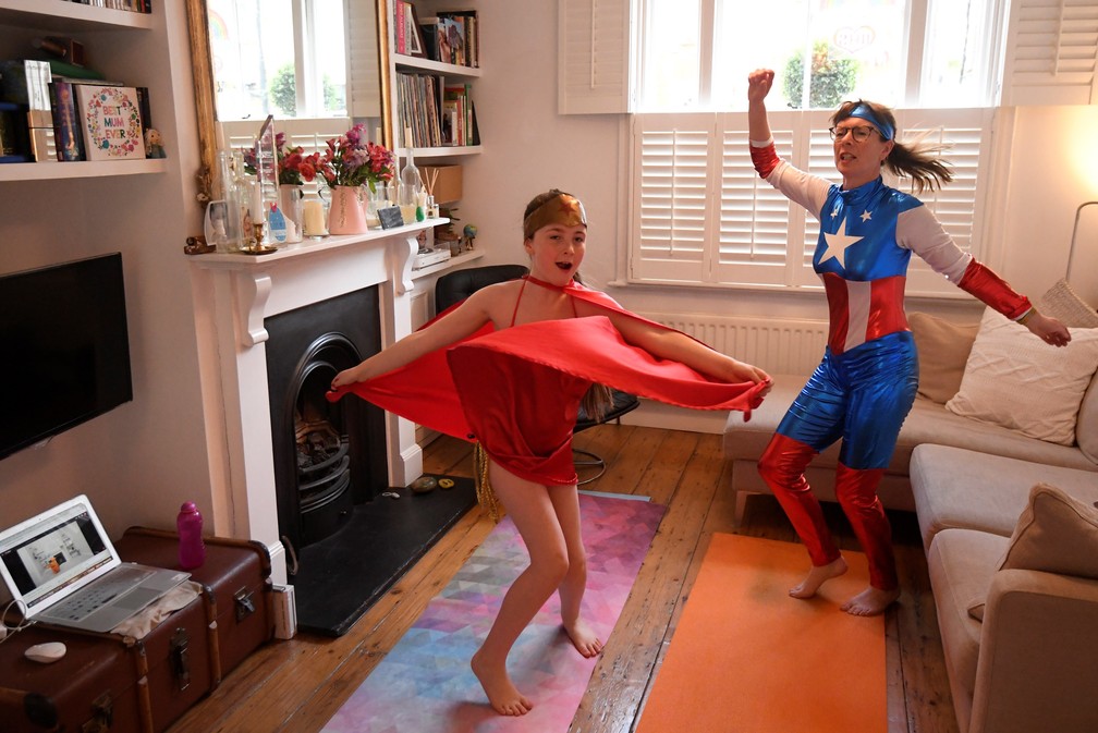 Jo Proudlove e a filha Eve, de 9 anos, acompanham uma aula diária de exercícios online vestidas como super-heróis em casa em Londres, no Reino Unido, durante isolamento para evitar a disseminação da doença por coronavírus (COVID-19) — Foto: Toby Melville/Reuters