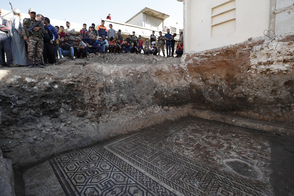 Pessoas observam enorme mosaico da era romana que foi descoberto em Rastan, na Síria  — Foto: Omar Sanadiki/AP
