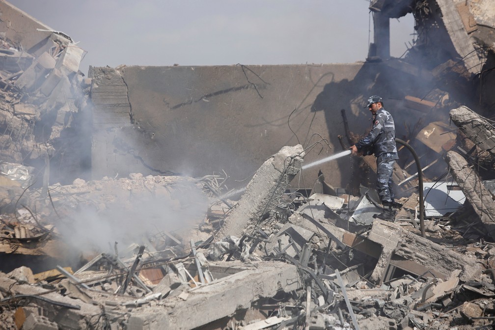 Bombeiro sÃ­rio apaga chamas em centro de pesquisa cientÃ­fico destruÃ­do apÃ³s ataque de EUA e aliados (Foto: Omar Sanadiki/Reuters)