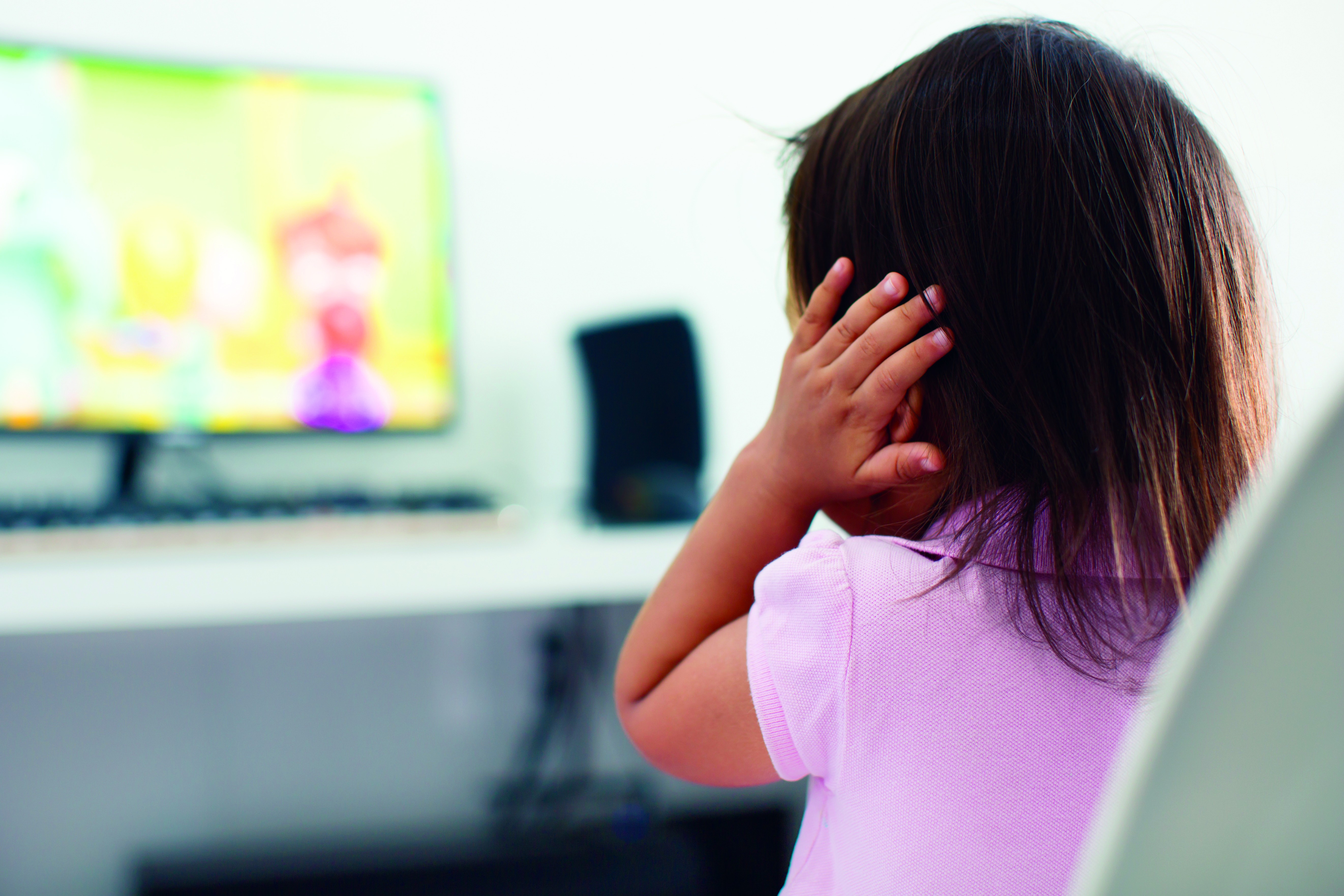 A child watching tv holding her ears because she is afraid of the sound; Child behavior theme (Foto: Getty Images/iStockphoto)
