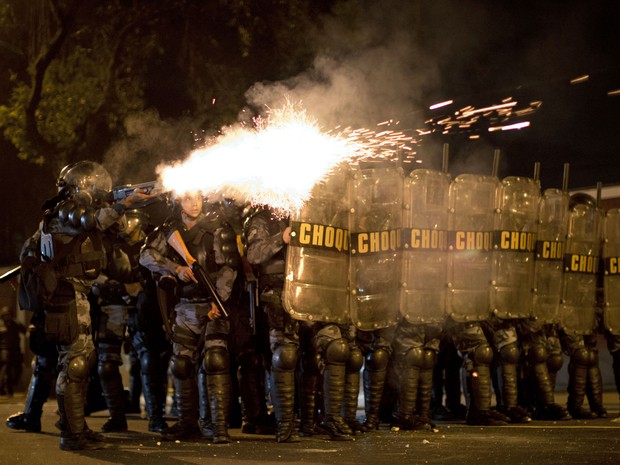 Policiais disparam bombas de gás lacrimogêneo contra manifestantes no Palácio Guanabara, no Rio, nesta segunda-feira (12). (Foto: Felipe Dana/AP)