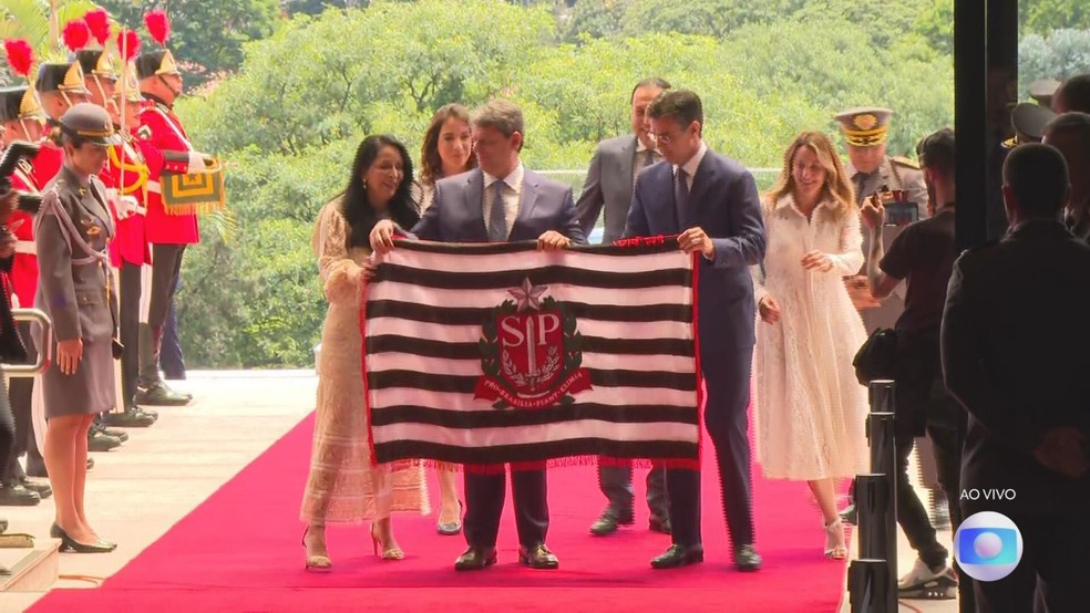 O governador empossado Tarcísio de Freitas recebe o pavilhão do estado das mãos do antecessor, Rodrigo Garcia, em cerimônia no Palácio dos Bandeirantes — Foto: Reprodução/TV Globo