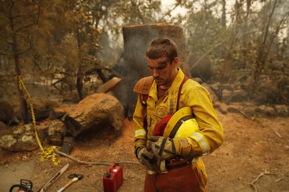 Bombeiro descansa em meio a floresta queimada no incêndio Camp Fire, na California — Foto: John Locher/AP Photo