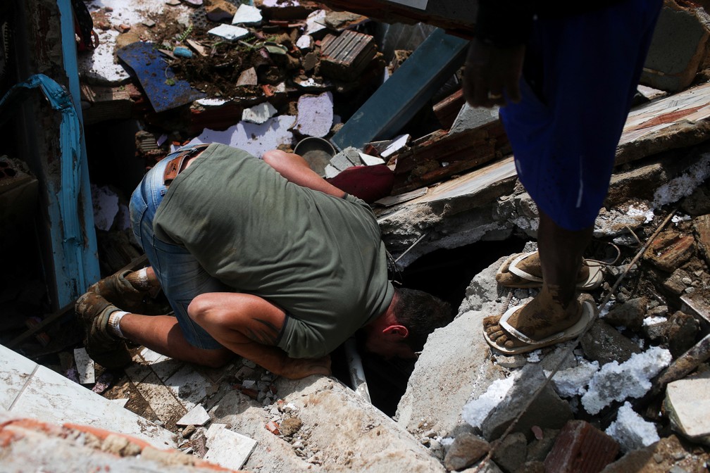 Um homem procura por vítimas após deslizamento no Morro da Oficina, em Petrópolis (RJ) — Foto: Ricardo Moraes/Reuters
