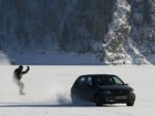 Russo pratica snowboard puxado por carro na superfície congelada de rio