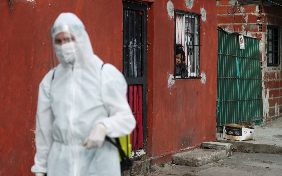Criança observa funcionário com roupa protetora durante operação contra a disseminação do coronavírus em Beccar, nas proximidades de Buenos Aires, na Argentina, em foto de 17 de junho — Foto: Reuters/Agustin Marcarian 