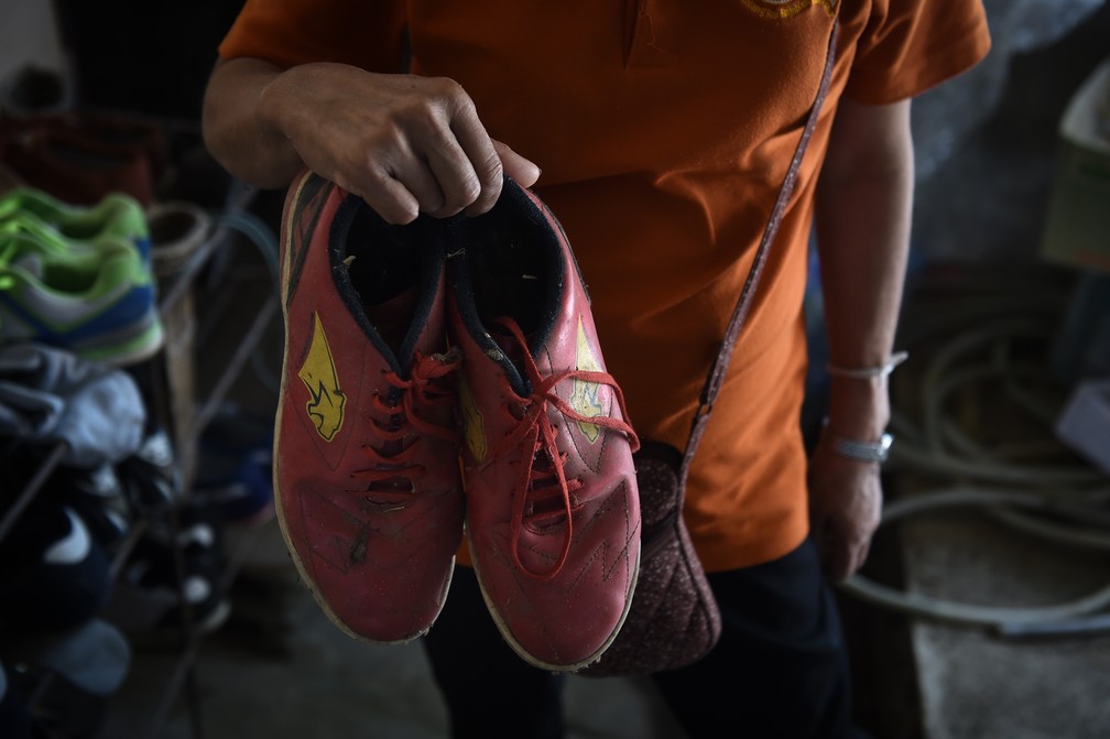 Tia-avó de garoto preso em caverna na Tailândia mostra os sapatos deixados para trás (Foto: Lillian Suwarumpha / AFP)