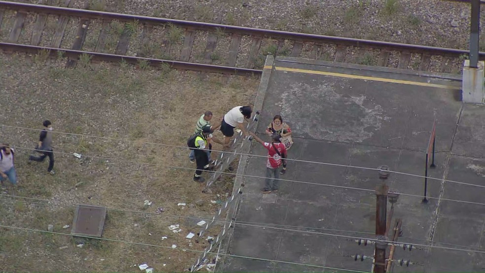 Mulher encontra dificuldade para subir em escada após caminhada nos trilhos dos trens da Supervia — Foto: Reprodução/ TV Globo