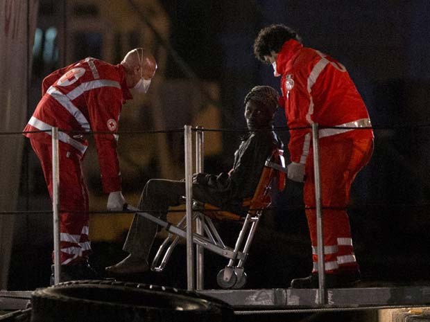 Sobrevivente é transportado em cadeira ao desembarcar de barco da guarda costeira italiana no porto de Catania na noite desta segunda-feira (20) (Foto: AP Photo/Alessandra Tarantino)