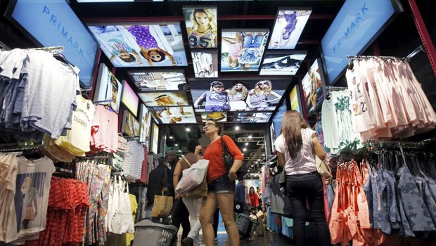 Consumidora observa roupas na loja Primark, especializada em fast fashion, roupas mais baratas e descartáveis (Foto: Divulgação)