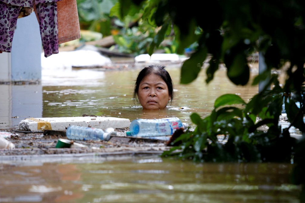 Mulher na cidade de Hoi An atravessa rua com água na altura do pescoço; cidade sofreu enchente após passagem do tufão Damrey (Foto: Kham/Reuters)
