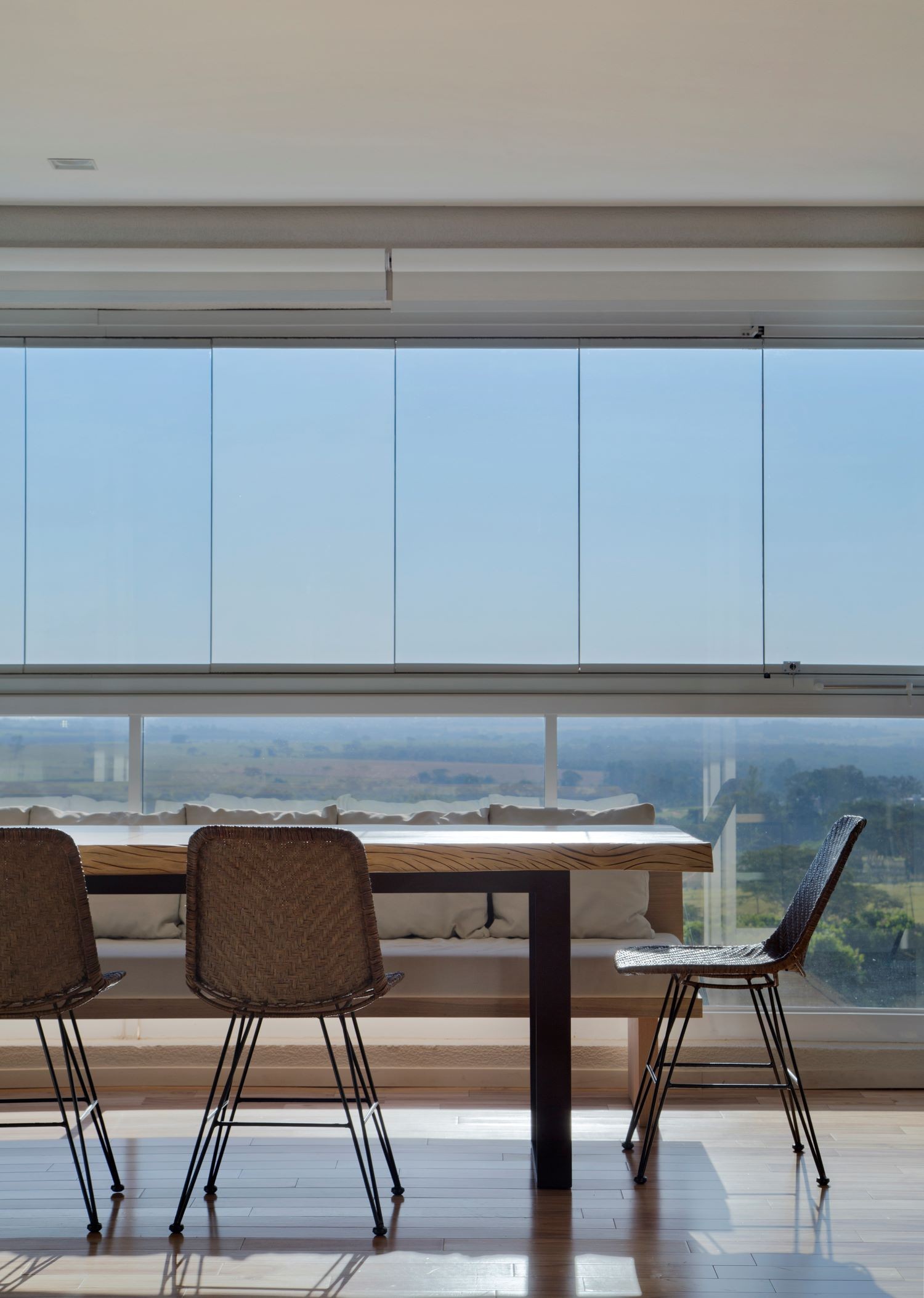 VARANDA | O fechamento em vidro permite que os moradores contemplem a vista. A mesa, em madeira de demolição, é da Tabocaecodesign (Foto: Divulgação / )