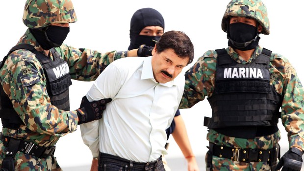 O líder do cartel de drogas Joaquin "El Chapo" Guzman é escoltado por agentes das forças de segurança do México no aeroporto internacional da Cidade do México. Ele era considerado o inimigo público número 1 do país, ao chefiar um cartel que se transformou (Foto: Mario Guzmán/EPA/Getty Images)