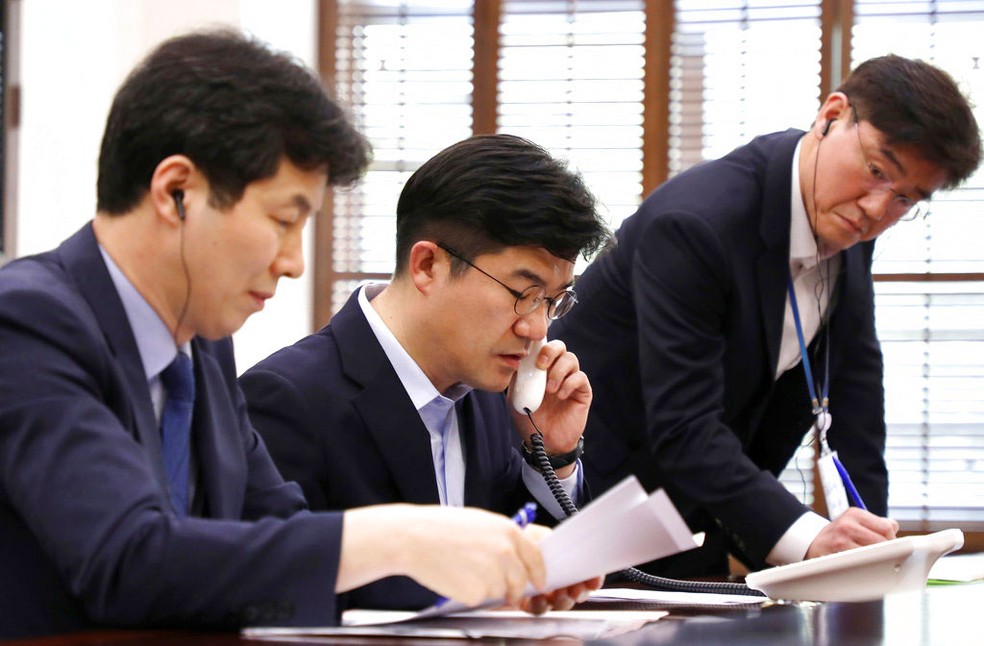 Funcionário do presidente sul-coreano fala ao telefone com a Coreia do Norte em um teste da linha direta entre mandatários dos dois países, que foi reativada desta sexta-feira (20)  (Foto: South Korea Presidential Blue House/Yonhap via AP)