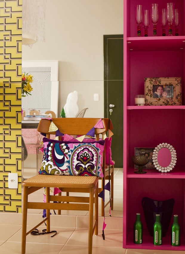 A estante na cor pink acompanha o tom da viga neste apartamento assinado pela arquiteta Andrea Murao. Ao lado, o espelho amplia a sala, que tem piso e paredes em tons neutros (Foto: Edu Castello)