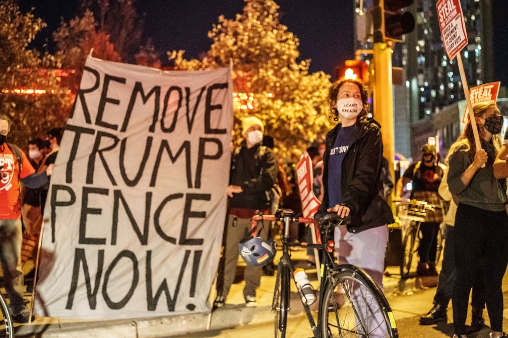 Pessoas seguram uma faixa onde se lê 'Remova Trump Pence agora!' durante protesto contra o racismo e as questões com a eleição presidencial em Minneapolis, Minnesota, nesta quarta-feira (4) — Foto: Kerem Yucel/AFP